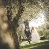 Garden villa wedding Italy. Romantic walk for bride and groom on the grass among the olive trees of the villa.