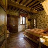 Painted door viewing the bedroom with antique bed and wooden wardrobe and window. wedding tuscany villa