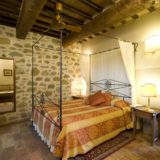 View of one of the bedrooms with iron bed structure, wooden mirror and elegant smooth lighting. wedding tuscany villa