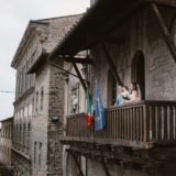 Bridal couple and their daughter on the balcony in Cortona town hall
